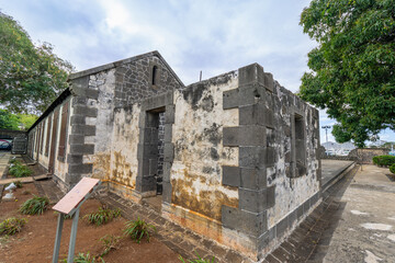 Fototapeta premium The weathered facade of a historic building at Sucre Adventure Park, Mauritius. Stone walls and arched windows offer a glimpse into the island's rich colonial past. Sucre Adventures, Mauritius.