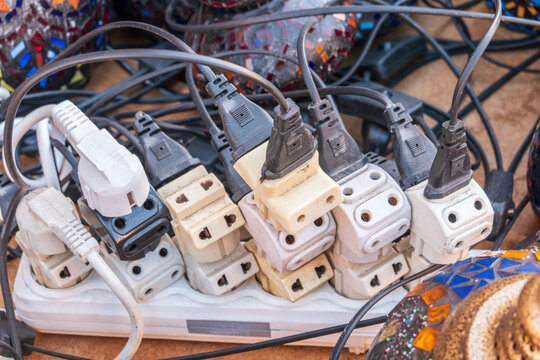 Old and damaged electric adapter power plug has many appliances are plugged outlet socket concept of risk danger overloaded current electrical. Overloaded power plugs, close up