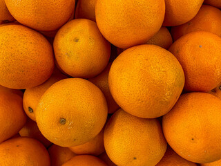 Close up of stack of mandarin oranges on wooden table taken from above.