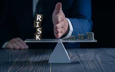 Planning and strategy in business. hand in a business suit blocking the word "RISK" while stacked coins on other side of seesaw demonstrate the concept of balancing risk and reward.