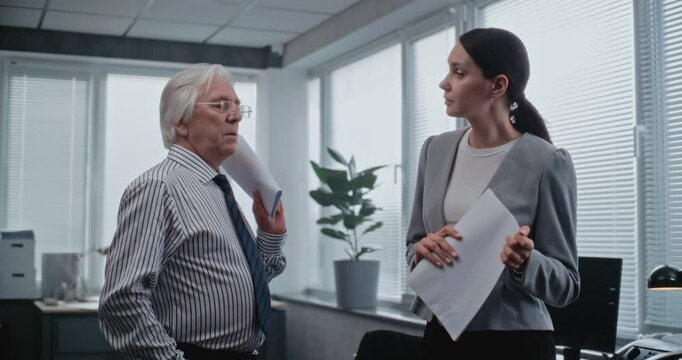 Teamwork in modern office: Senior team leader and female employee have discussion. Two marketing professionals discuss business strategy, brainstorm project ideas. International finance corporation.