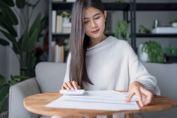 Businesswoman Accountant analyzing investment charts Invoice and pressing calculator buttons over documents. Accounting  at home