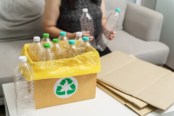 Home recycle eco green zero concept Woman throwing empty plastic bottle in recycling bin with yellow garbage bags at home.