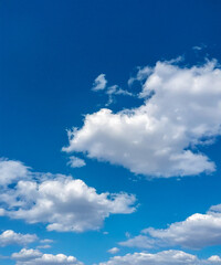 Fototapeta premium A peaceful scene of a blue sky dotted with soft, white cumulus clouds, perfect for backgrounds and design.