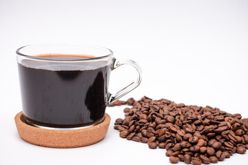 Cup of coffee and a pile of coffee beans next to it