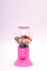Pink gumball machine with a clear glass container full of colorful gumballs