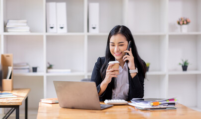 asian woman talking on the phone while working on computer in desk office. Searching on internet
