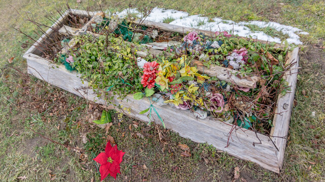wooden tombstone, deteriorating, plastic flowers, artificial flowers, modestly decorated, flowers, burial, cemetery, cross, christian