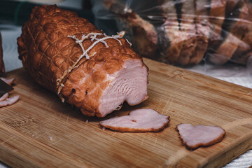 Piece of ham is cut on a wooden cutting board