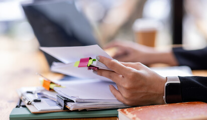 Business asian woman Reviewing Documents, business woman's hands meticulously reviewing a stack of...