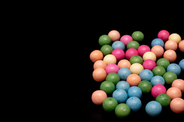 Bunch of colorful candy balls are spread out on a black background