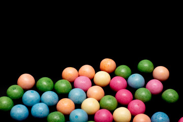 Bunch of colorful candy balls are spread out on a black background