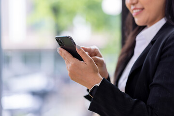 Portrait of a happy Asian businesswoman using mobile phone indoor, Asian businesswoman working in modern office.
