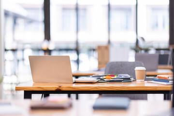 Laptop Computer, notebook, and eyeglasses sitting on a desk in a large open plan office space after working hours	
