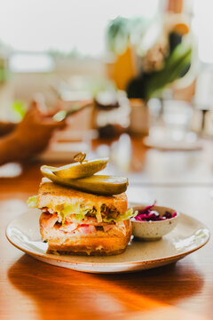 Cheese sandwich with pickles on a plate in cafe.