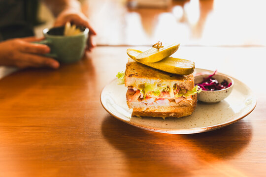 Cheese sandwich with pickles on a plate in cafe.