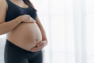 Pregnant woman holds hands on belly touching her baby caring about her health