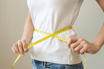 Diet, slim shape asian young woman standing, hand using measure tape around waist, body. Happy,...
