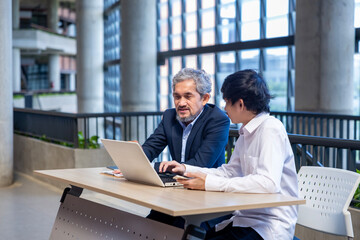 Asian senior professor is giving advice  to the college student on the research thesis while...
