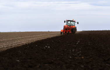 Fototapeta premium Tractor on the field during sunset.