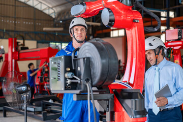 Fototapeta premium young caucasian technician in safety uniform check and maintenance welding robot machine,experienced staff beside,workers working with industrial robot in small industry