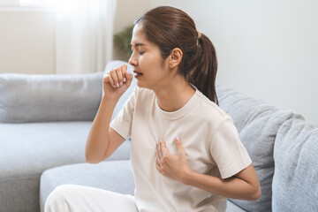 Health care of coronavirus concept, unhealthy and sickness, asian young woman, girl unwell and coughing, hand touch her chest, female sore throat suffering with symptom cough feeling bad at home.