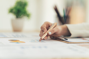Focused on the Details: Close-up of a hand meticulously analyzing financial data on a clipboard,...