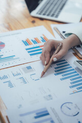 Analyzing the Data: Close-up of a hand pointing at a bar graph on a financial report, highlighting the crucial role of data analysis in business.  