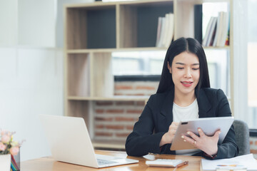 Confident Professional:  A young businesswoman confidently browses a tablet in her modern office, showcasing her tech savviness and professionalism.  