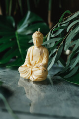 Handmade wax candle in the shape of Buddha against a tropical background