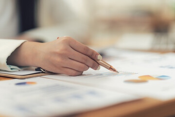 Analyzing Financial Data: Close-up of a hand meticulously reviewing financial charts and graphs,...