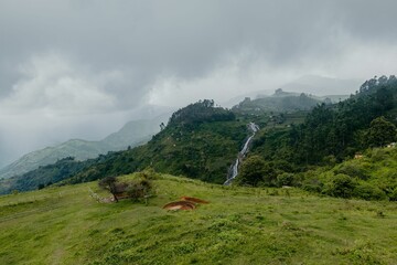 Scenic view of lush green hills and waterfall.