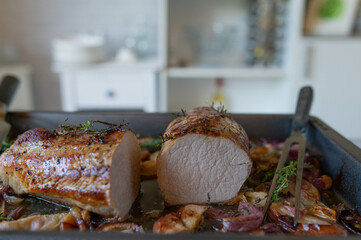 Homemade oven roasted pork loin with apples and onions on a baking tray