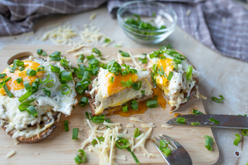 Homemade vegetarian sandwich with fried mushrooms, fried egg and cheese on a wooden cutting board in the kitchen