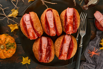 Halloween background. Homemade hot dogs with bloodied fingers on dark table for Halloween. Themed...