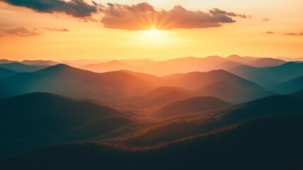 Fototapeta premium A vibrant sunset over a mountain range with rolling hills and a glowing sky.