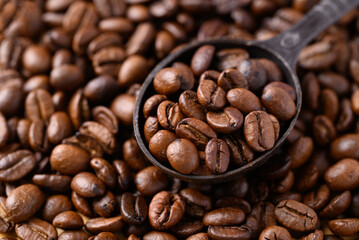 Roasted coffee bean (Arabica coffee) in spoon with roastedcoffee bean background