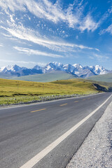 Asphalt highway road and green grassland with snow mountain natural landscape under blue sky. road trip.