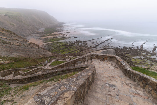 Playa de Barrika vista desde la parte superior de las escaleras con las rocas cubiertas por algas en un d&iacute;a nublado