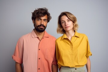 A man and a woman are standing next to each other, both wearing yellow shirts