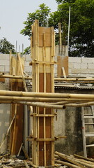The pillars of a building that are still wrapped in plywood and wood as a mold for the pillars of the building

