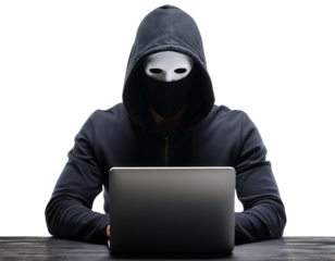 Anonymous hacker in a hoodie using a laptop on a dark table.