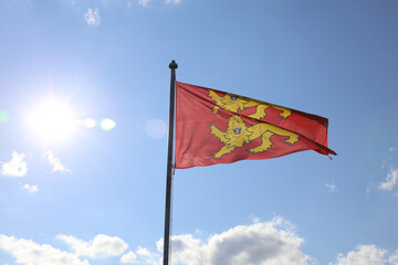 Flag of Normandy, two yellow lions on a red background, fluttering on a sunny sky.