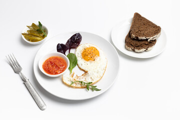 Fried egg on the plate, pickled cucumbers and bread,