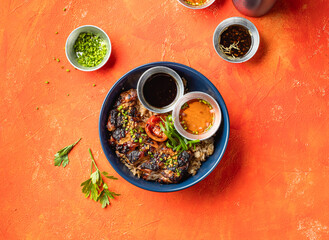 Lemongrass Grilled Chicken Inasal Rice with dipping Sauce and Green Onion isolated on orange...