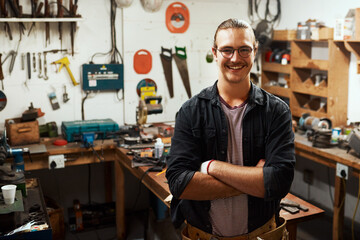 Happy man, portrait and carpenter with confidence for timber, woodwork skill or talent in garage workshop. Young, male person or professional artisan with smile or arms crossed in carpentry business
