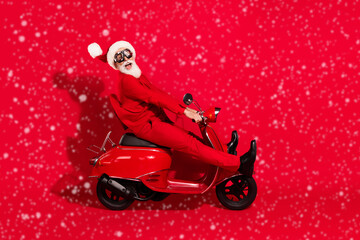 Full body profile photo of cool white hair elder man ride bike wear santa cap red suit eyewear...