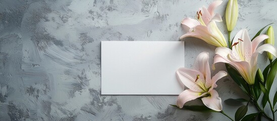 Obraz premium The Template Is A Blank Paper And An Envelope With Space For Text On A Gray Background With Lily Flowers Flat Top View A Place To Copy