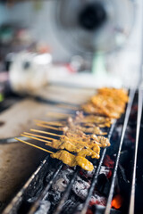 Pork satay grilling on stove or Moo satay at the market. The famous Thai street food.