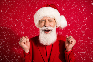 Photo of happy cheerful old man christmas santa claus hat winner celebrate isolated on red color background